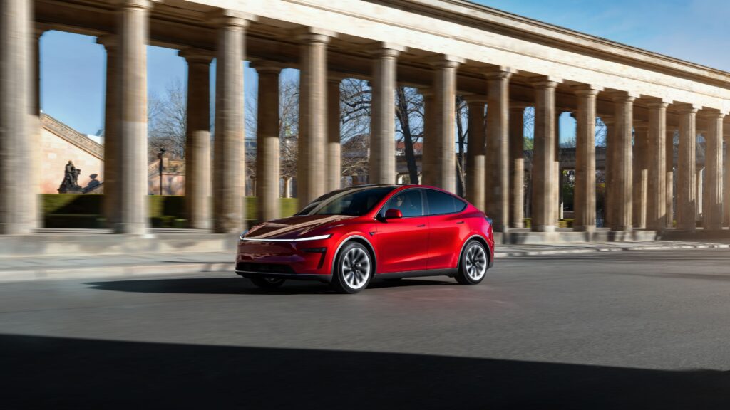 Tesla Model Y in red driving past a colonnade – Tesla Model Y price in India